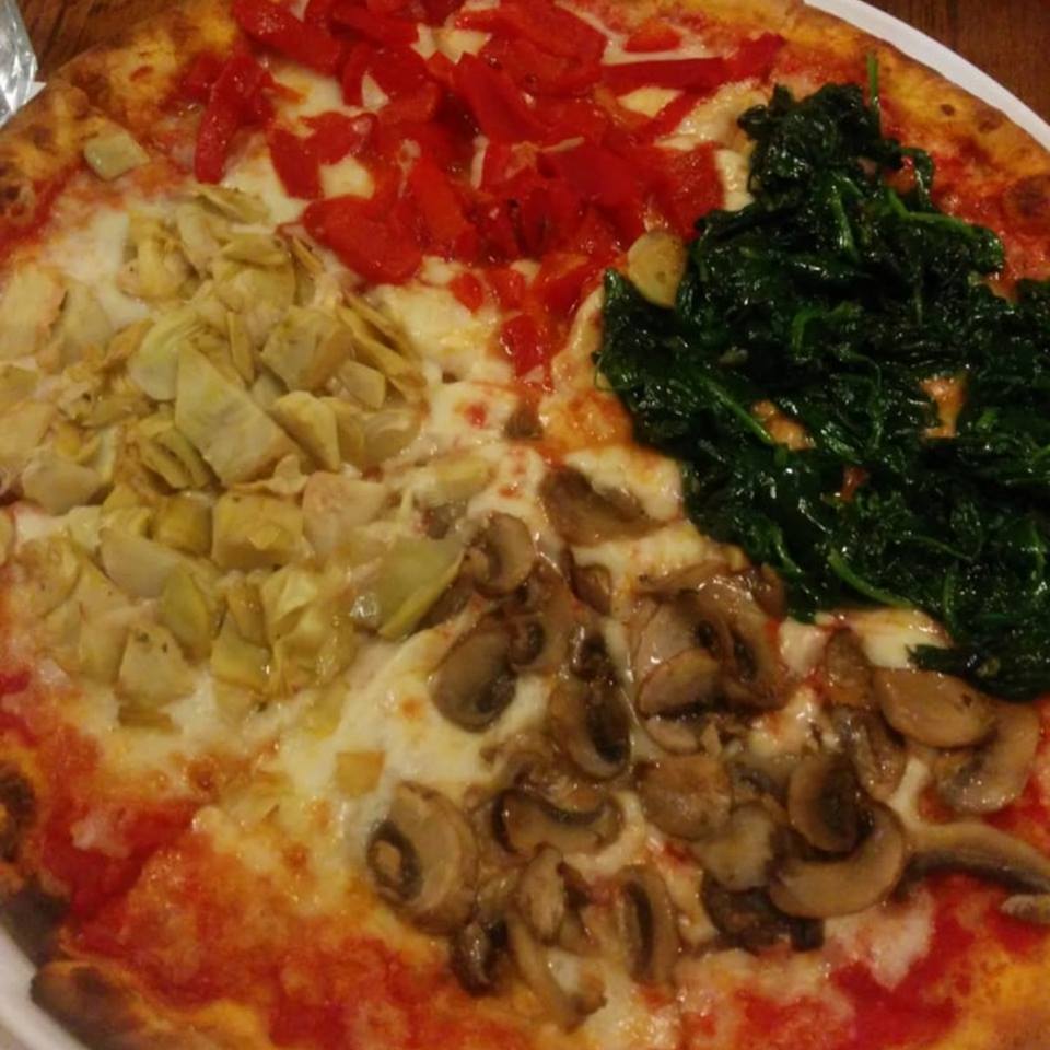 PIZZA STAGIONE A pizza divided into quarters and topped individually with mushrooms, artichokes,spinach, and roasted peppers